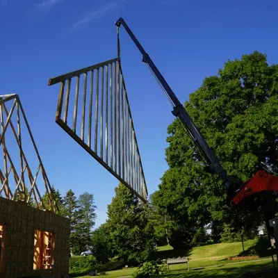 Prime Attachments telescopic boom installing trusses on structure showing high reach lifting for building construction