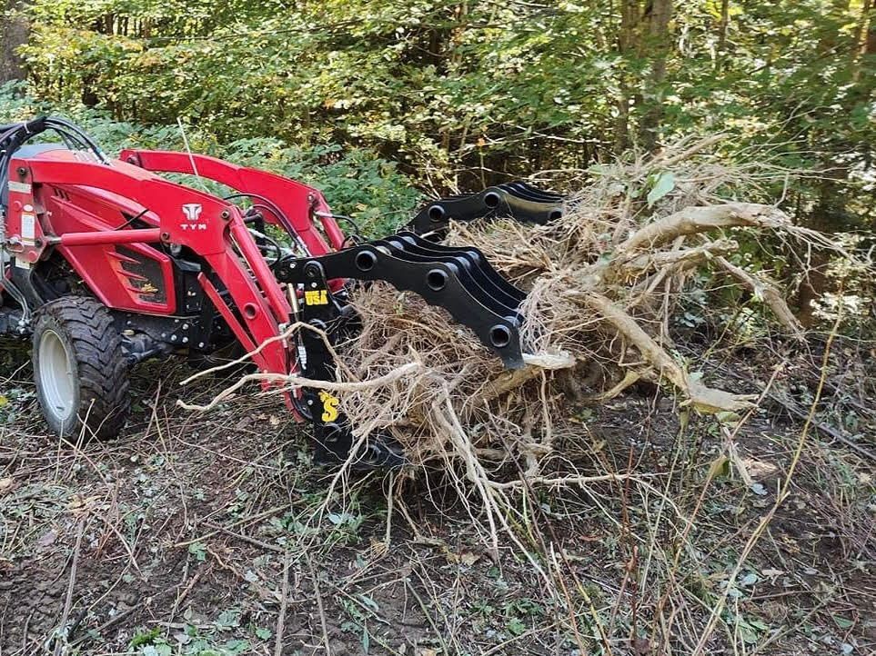 Stinger CCG compact tractor grapple pulling brush showing strong clamp force for clearing roots and debris