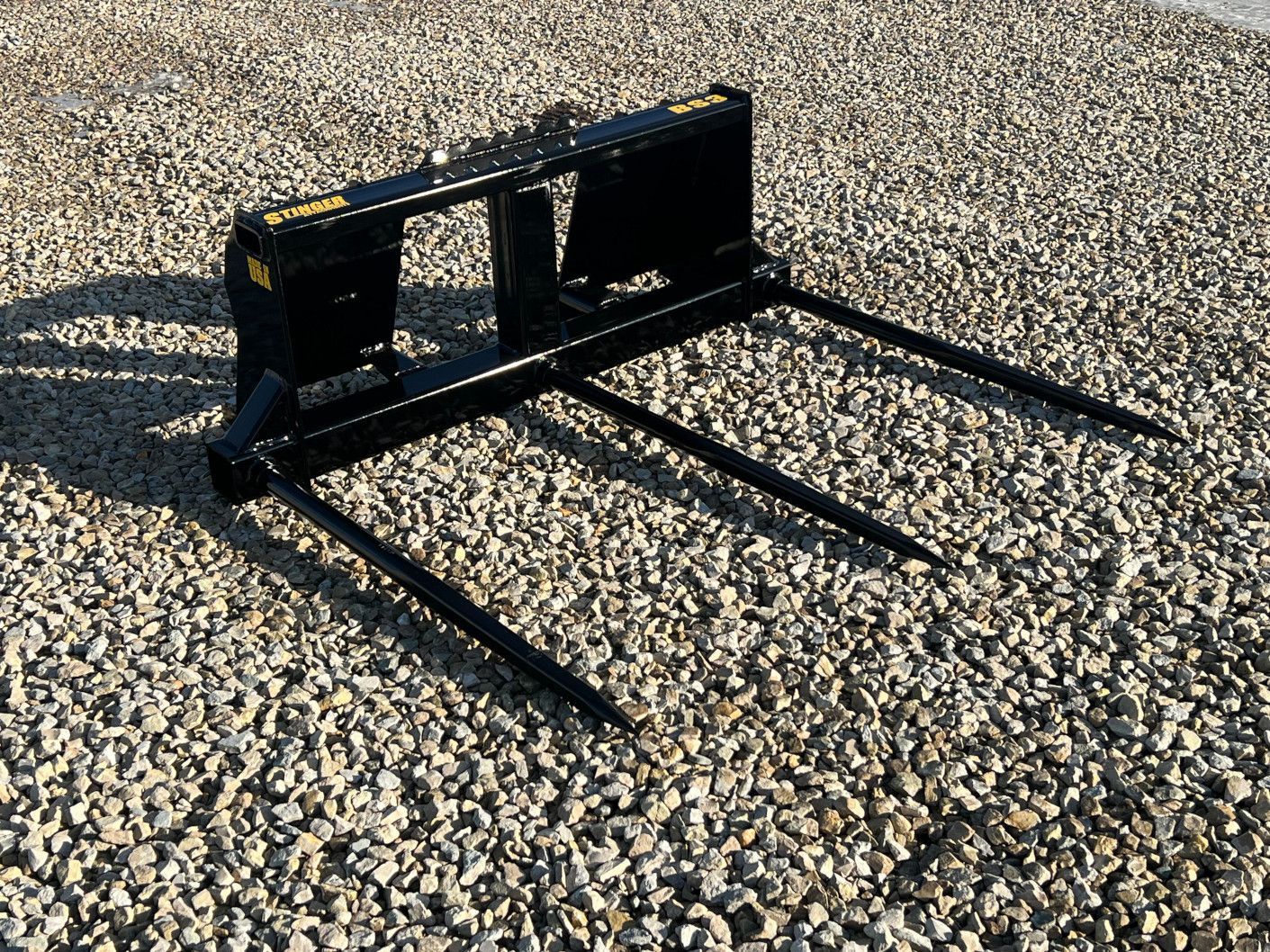 Stinger BS3 skid steer bale spear side view showing single main spear and dual stabilizer spears for hay handling