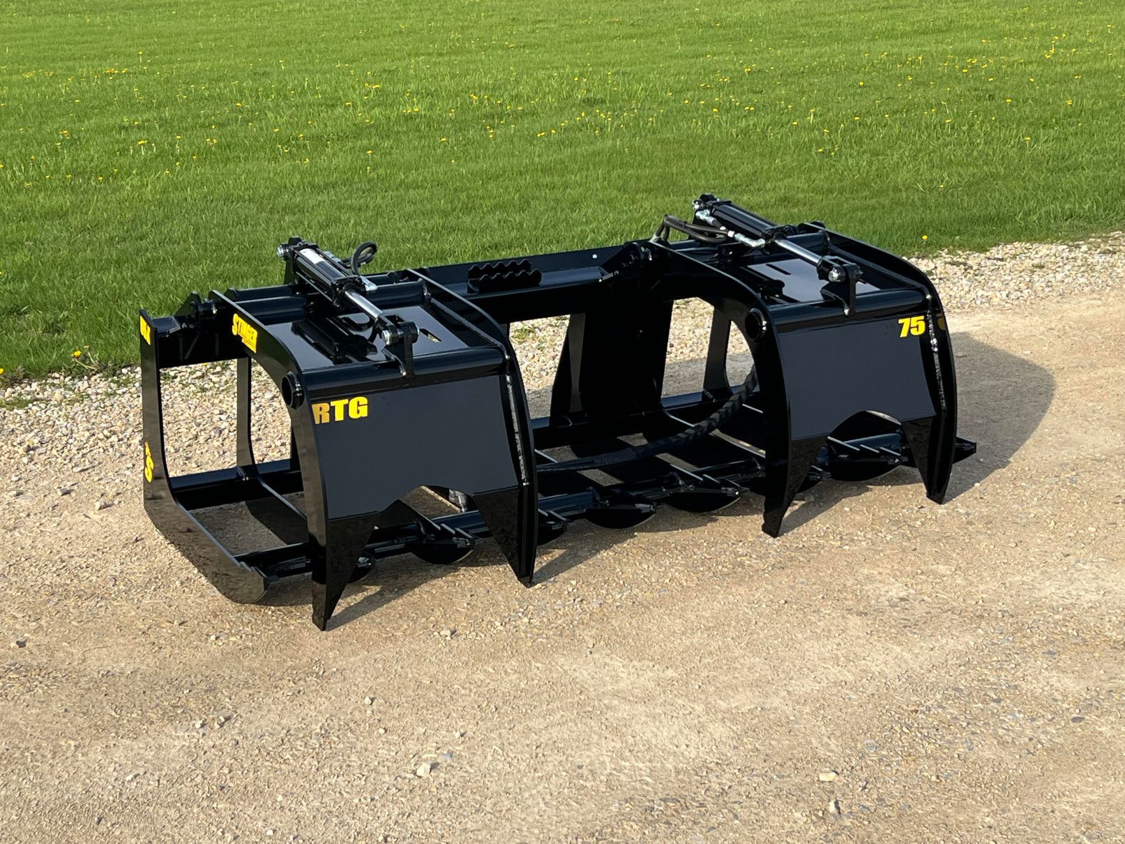 Stinger RTG tractor and skid grapple in field showing root grapple design and heavy duty tines for brush handling