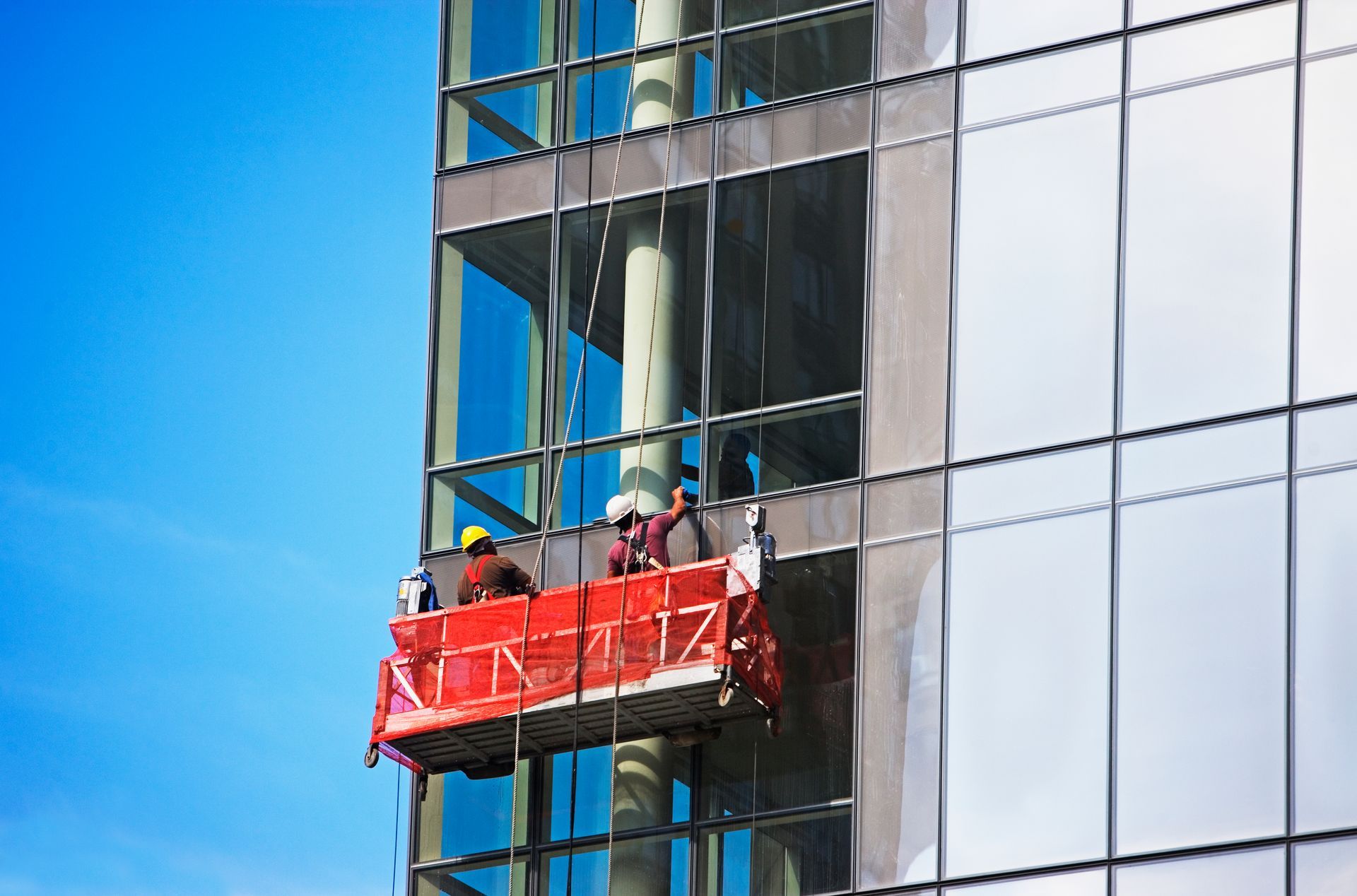 A group of construction workers are cleaning the windows of a tall building.