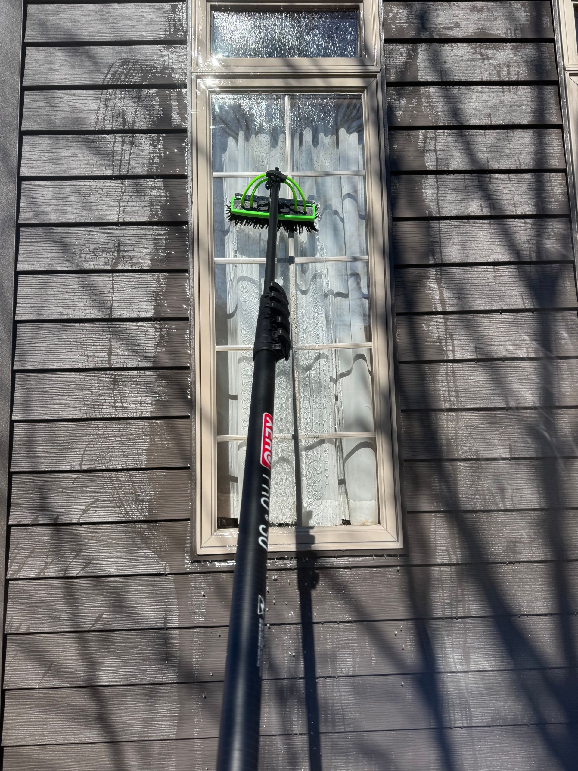 A window cleaner is cleaning a window on a wooden house