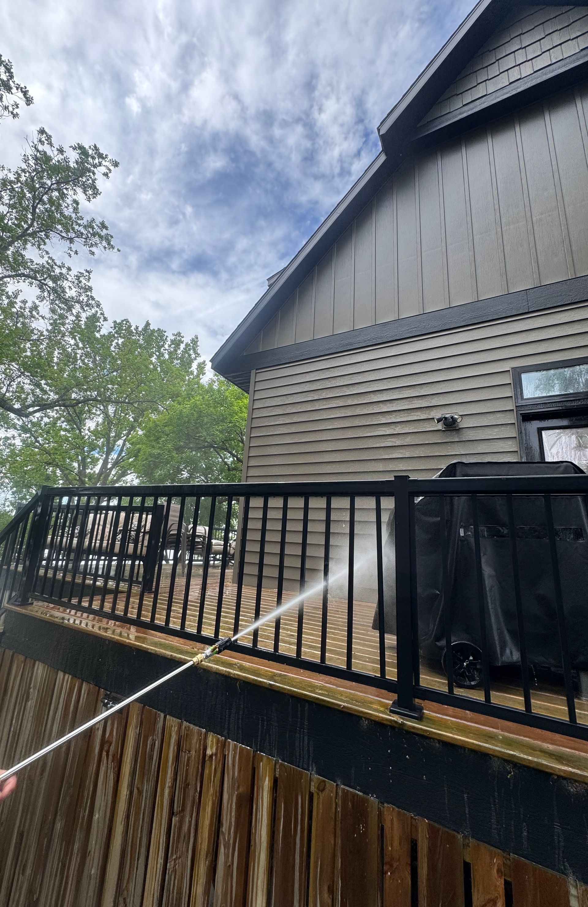 A person is cleaning a deck with a high pressure washer.