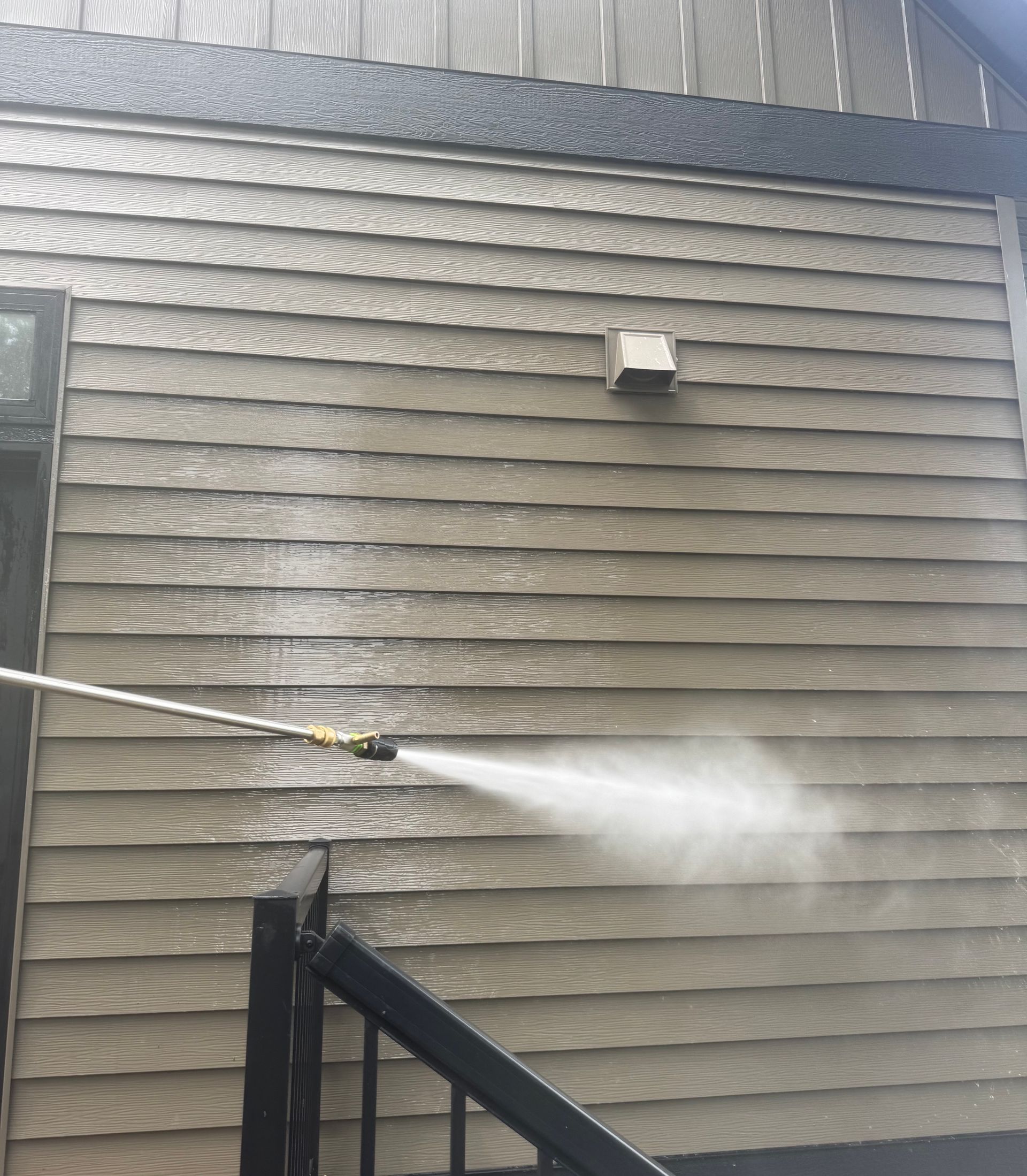 A house is being cleaned with a high pressure washer.