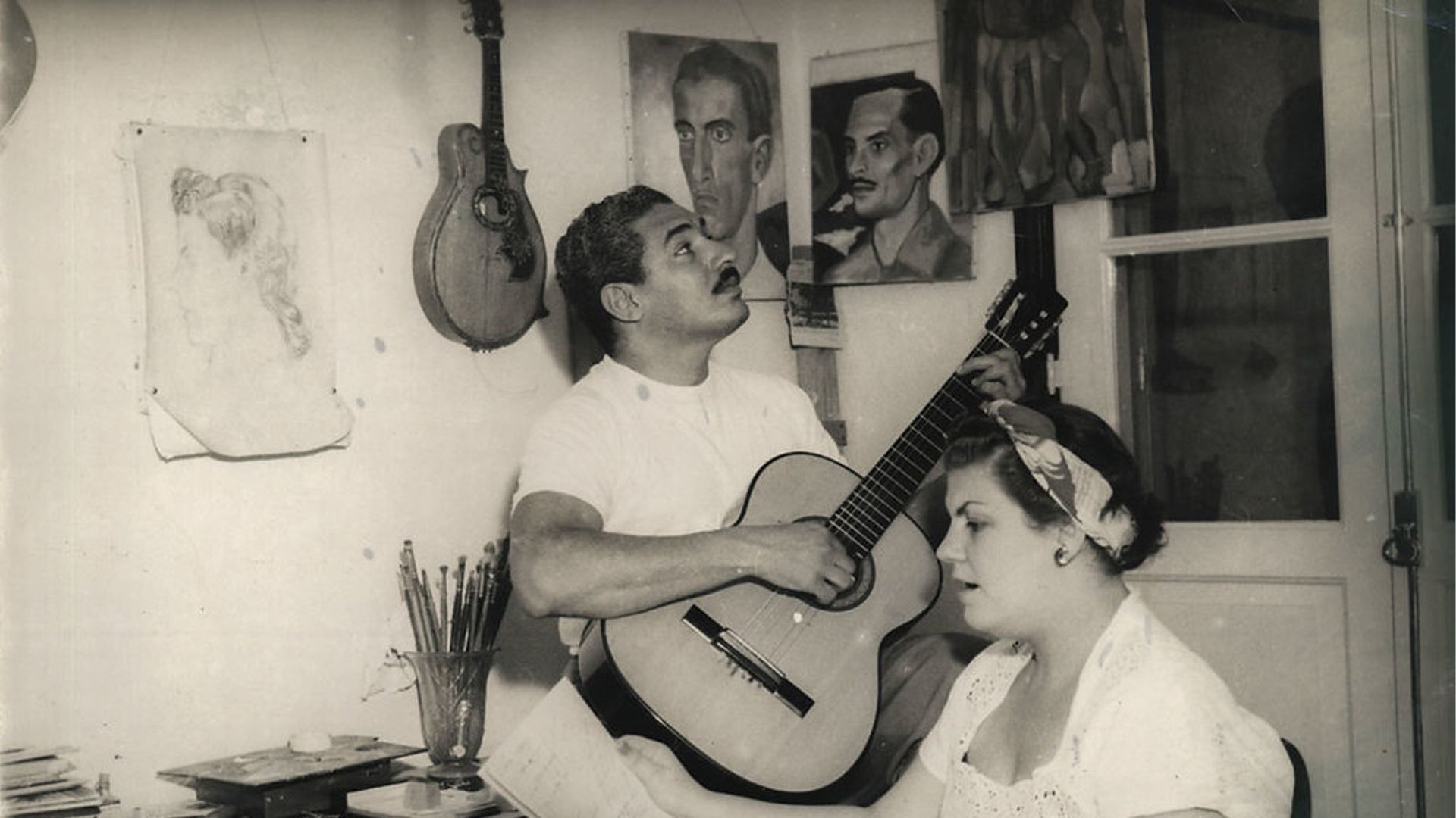 A man is playing a guitar to a woman in a black and white photo
