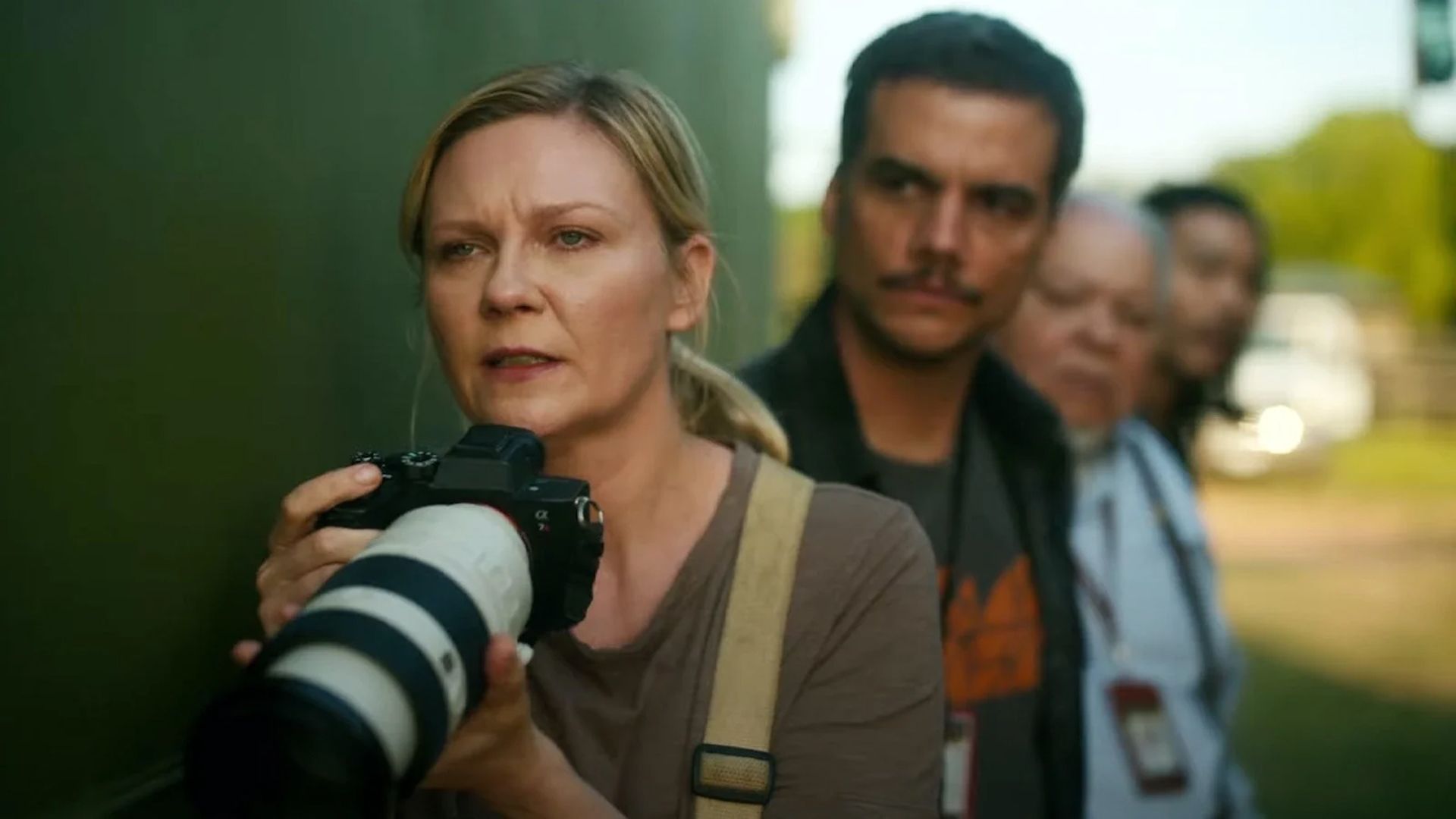 A woman is holding a camera in front of a group of people.