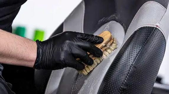 Worker cleaning a marine vinyl seat with  a brush