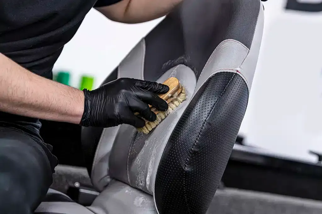 Worker cleaning marine vinyl seat with a brush