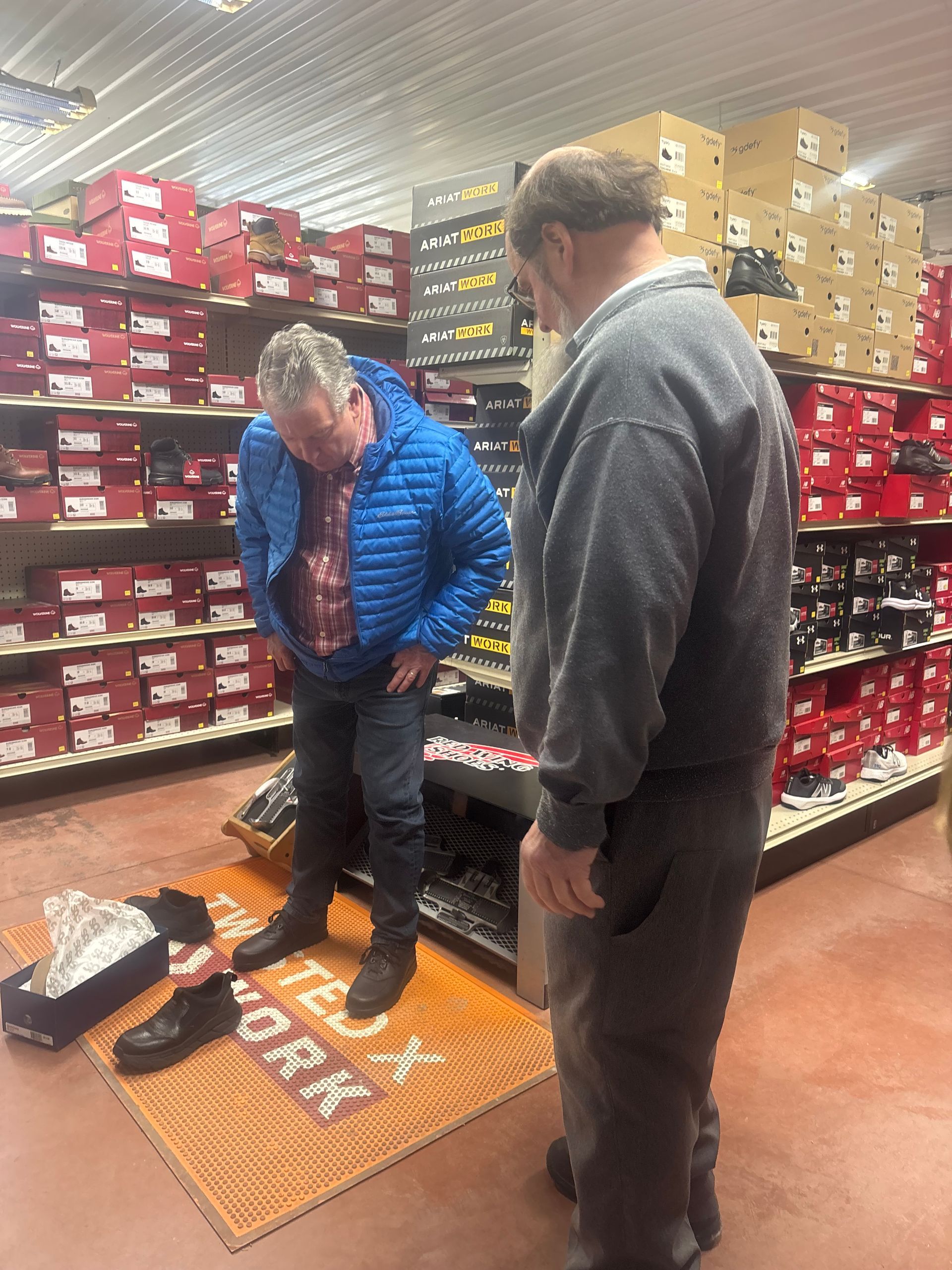 Shoes hanging and piled in a crowded market stall, showcasing a variety of colors and styles.