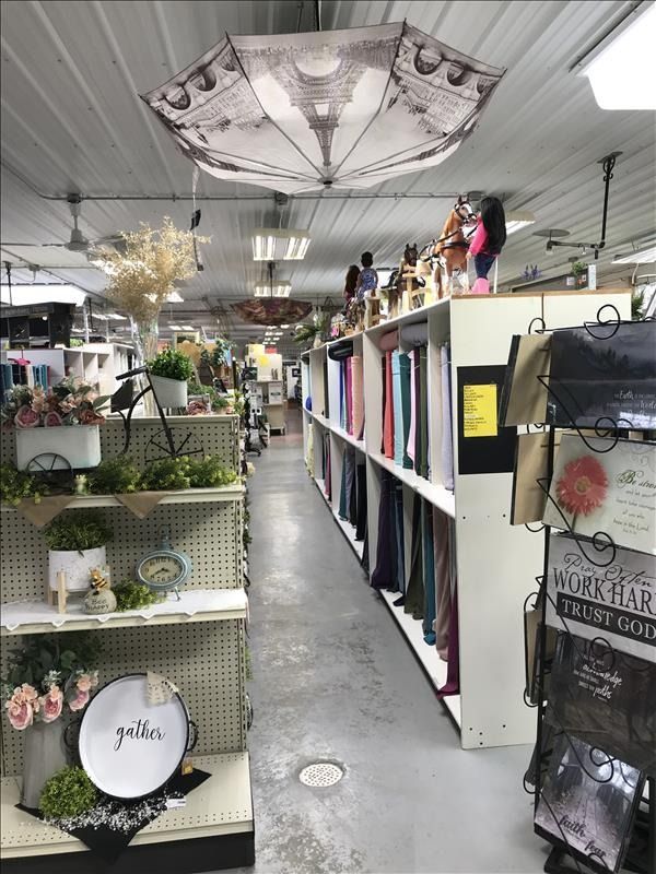 Interior of a store aisle with shelves of merchandise. An Eiffel Tower umbrella hangs overhead.