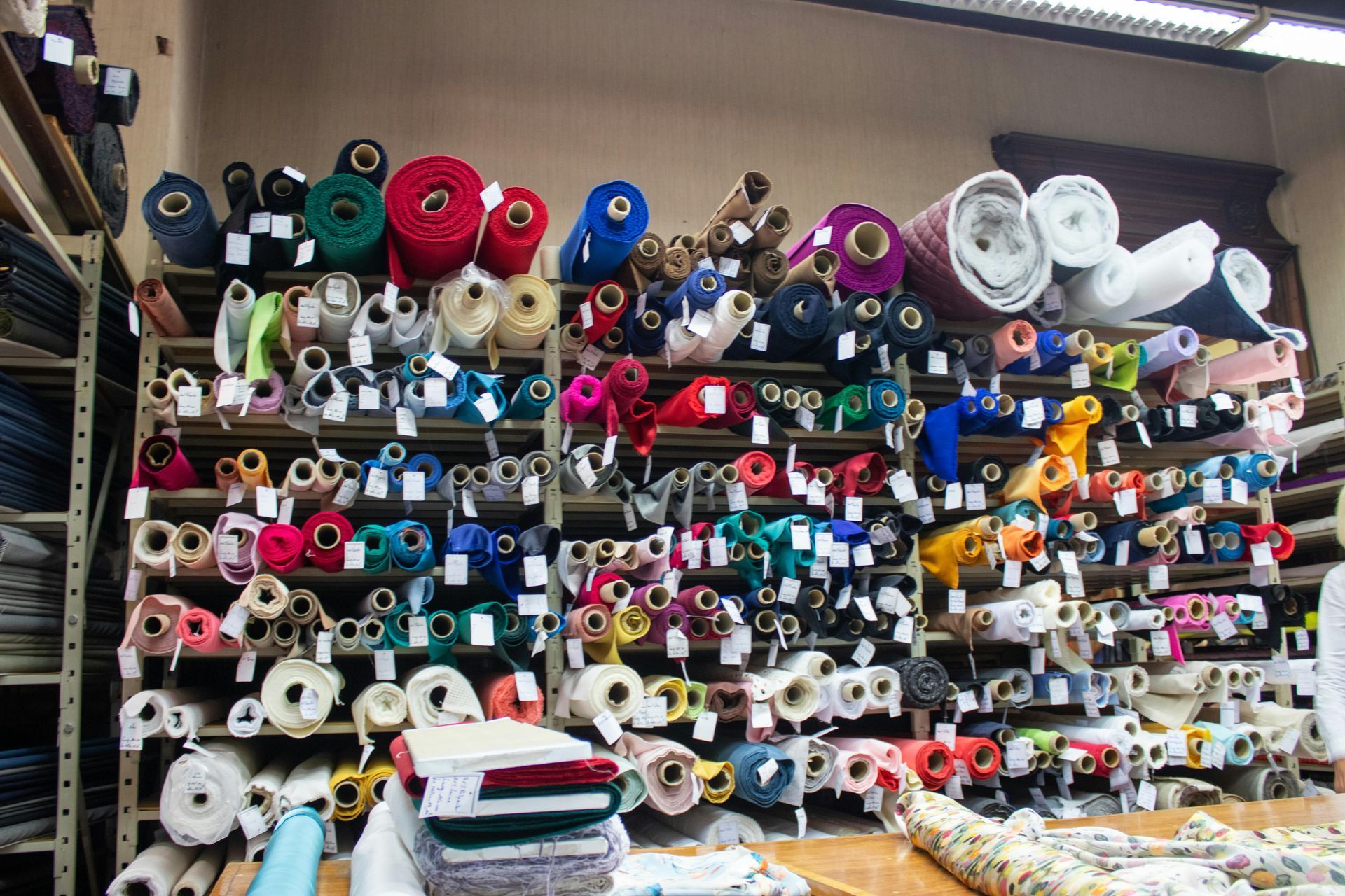 Shelves filled with various fabric rolls in a store; diverse colors and patterns.