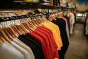 Rows of colorful t-shirts hanging in a retail store.
