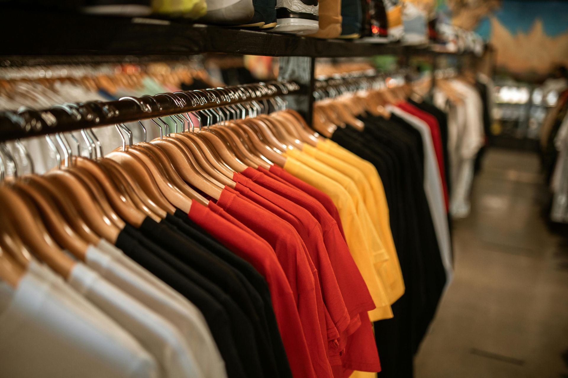 Rows of colorful t-shirts hanging in a retail store.