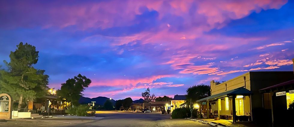 Evening scene: Colorful sunset over a town with buildings, trees, and street.