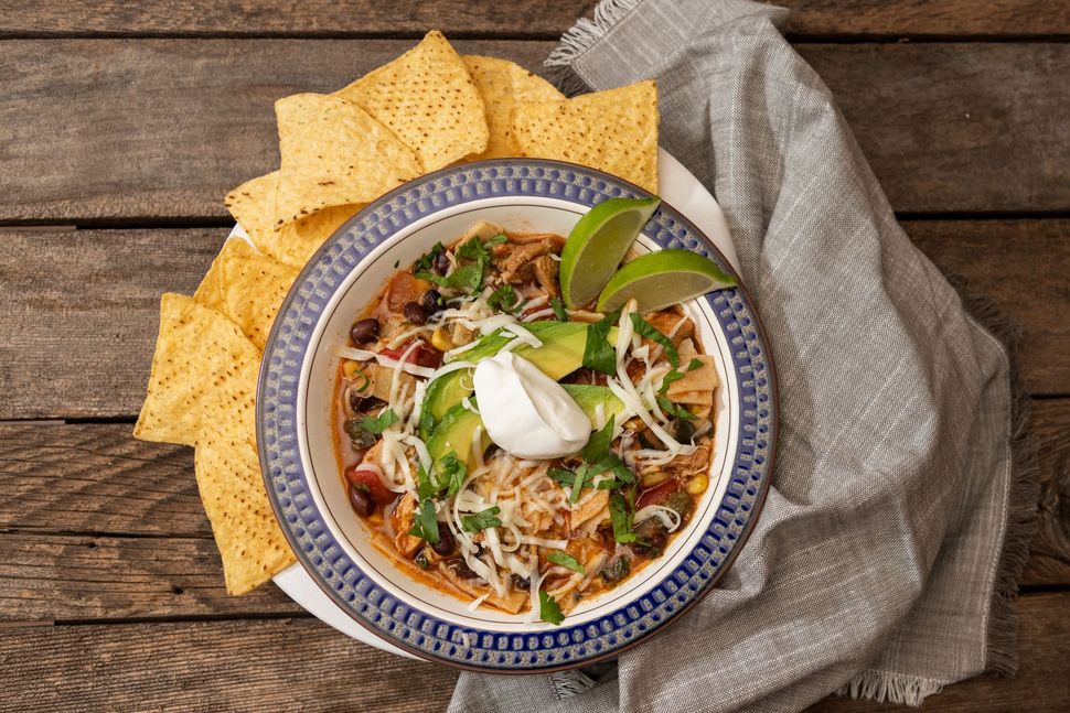 Chicken tortilla soup with toppings and tortilla chips.