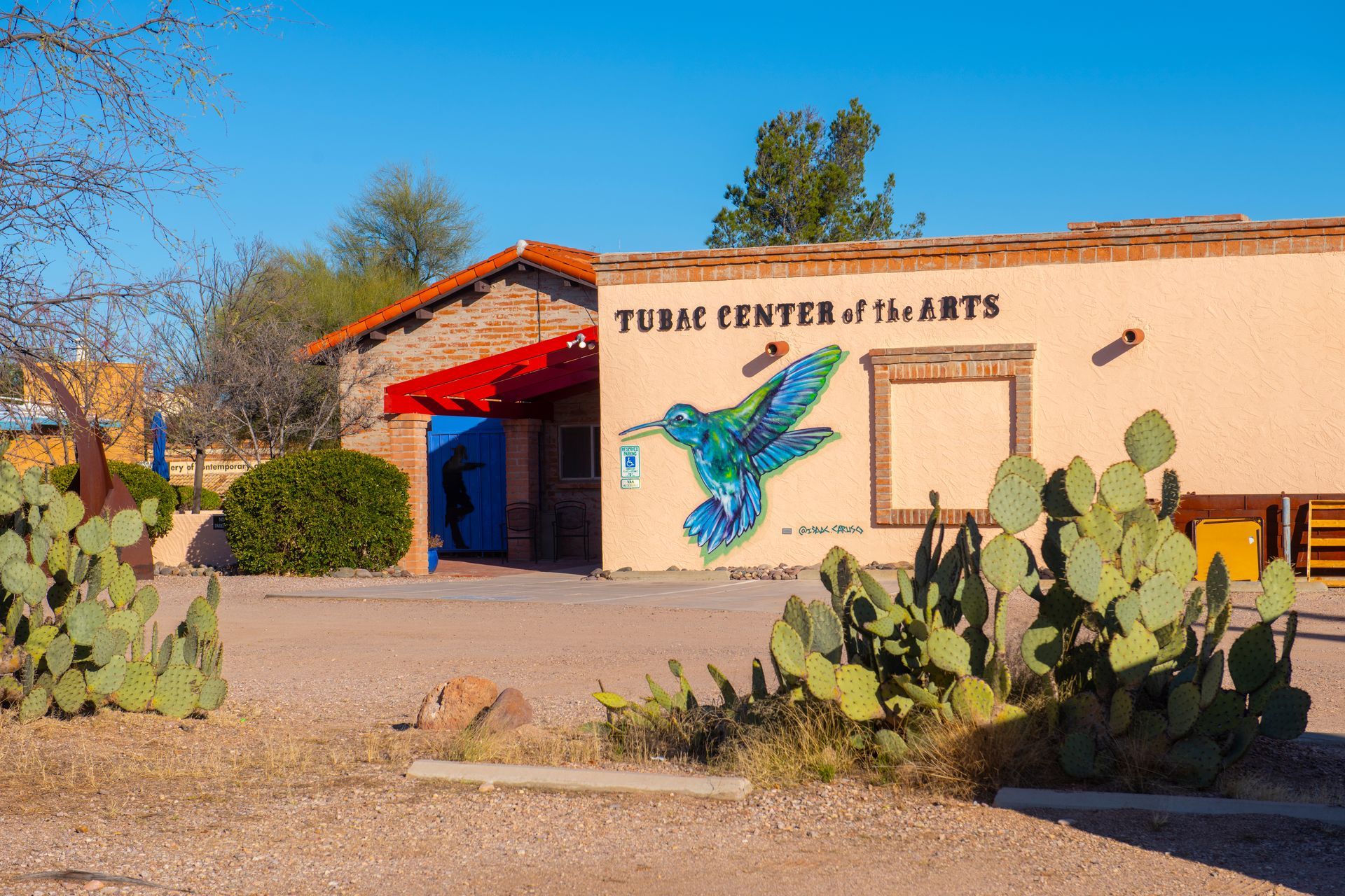 Tucson Center of the Arts with a hummingbird mural, cactus, and blue sky.