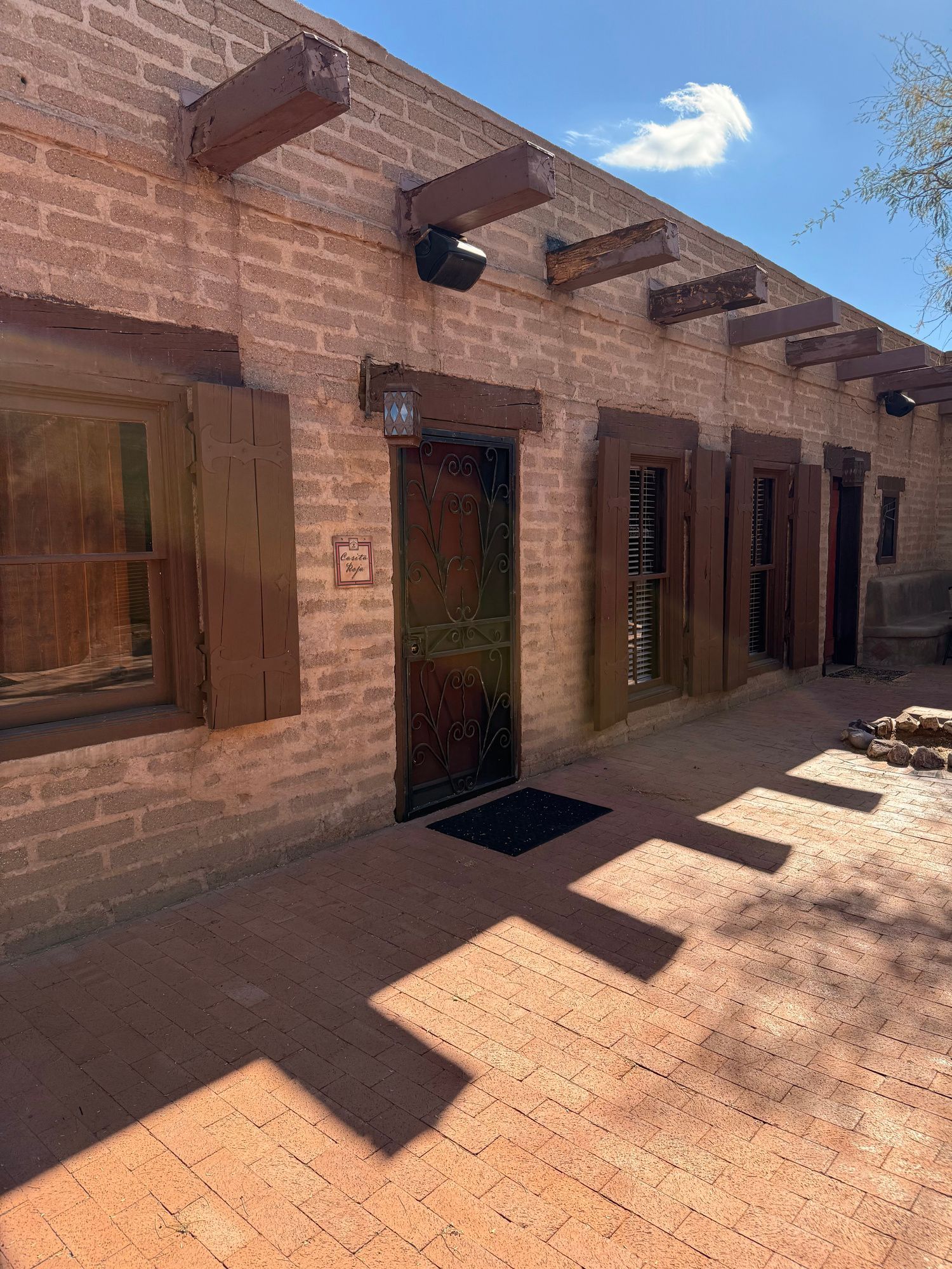 Brick building with wooden beams, door, shutters, and brick patio.