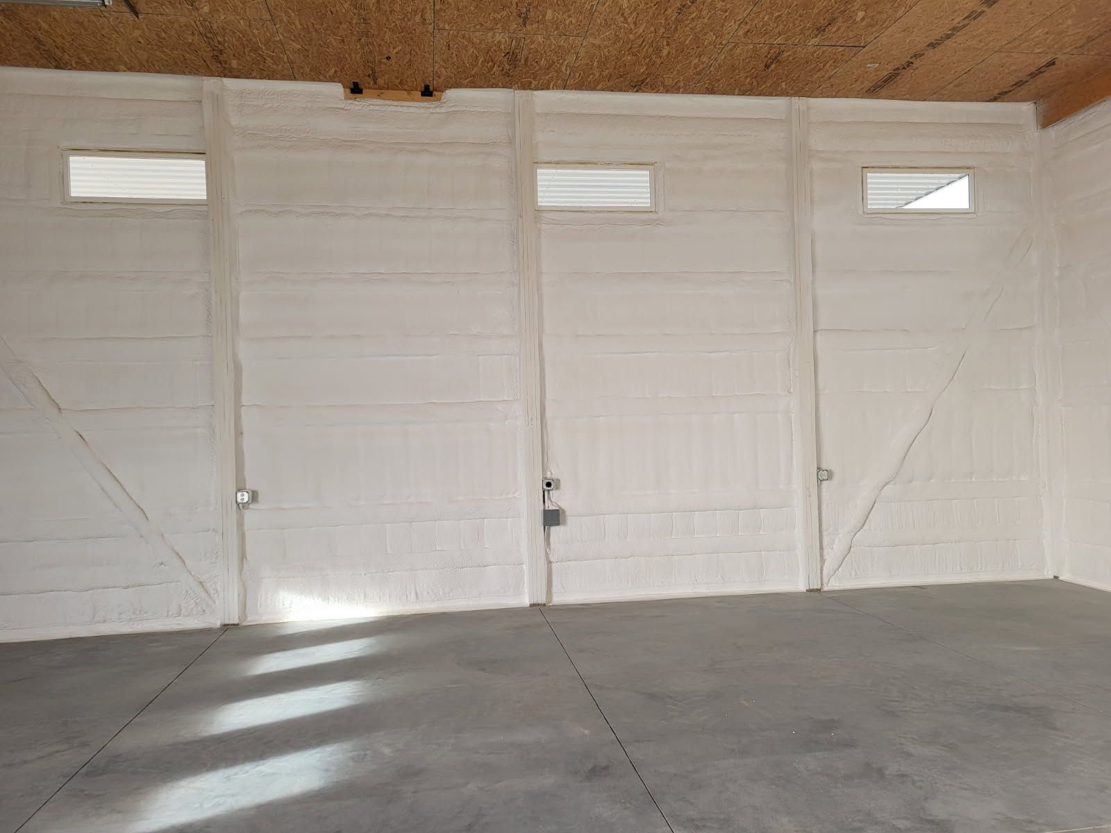 An empty garage with white doors and a concrete floor.