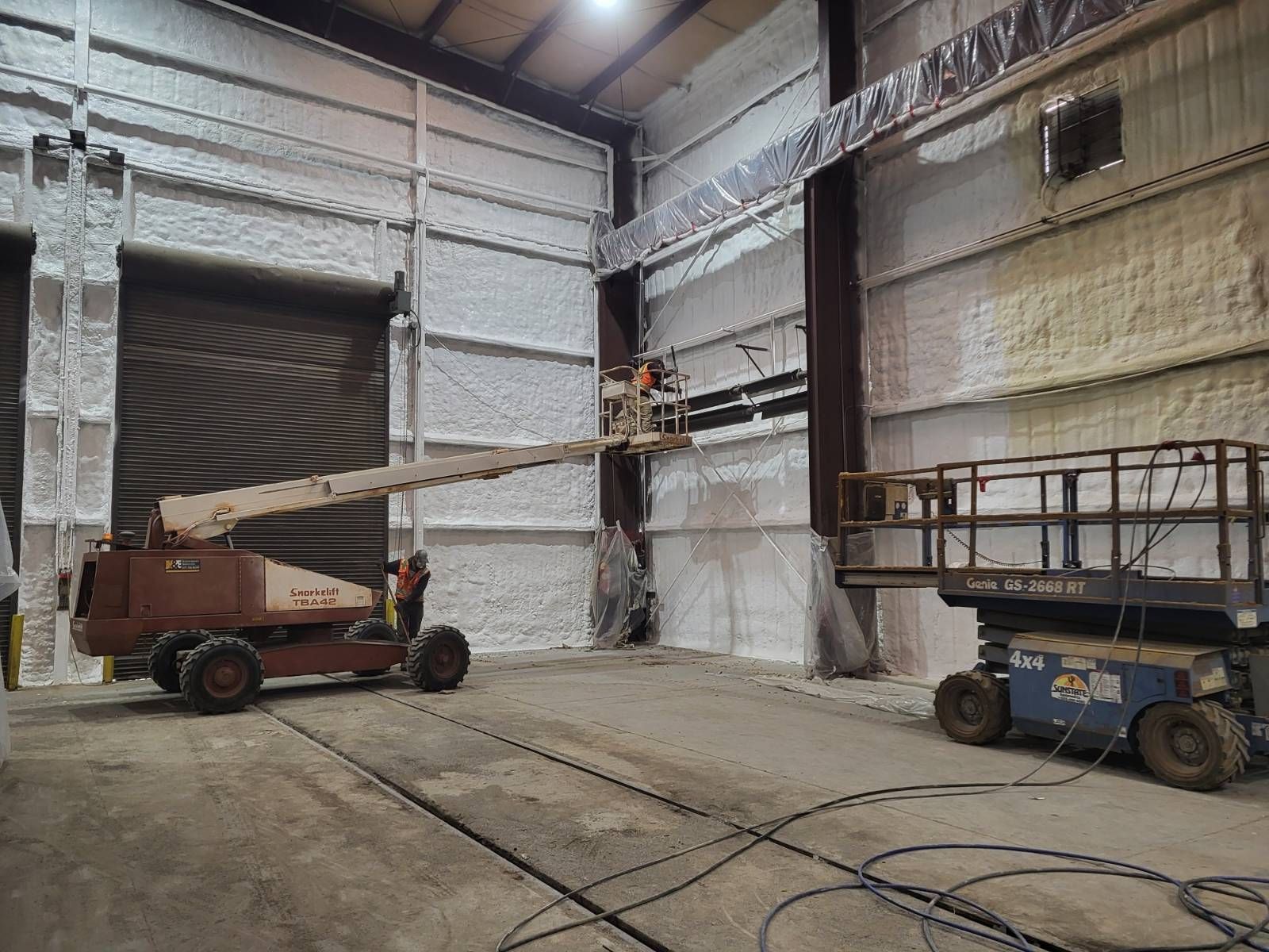 A man is standing on a lift in a warehouse.