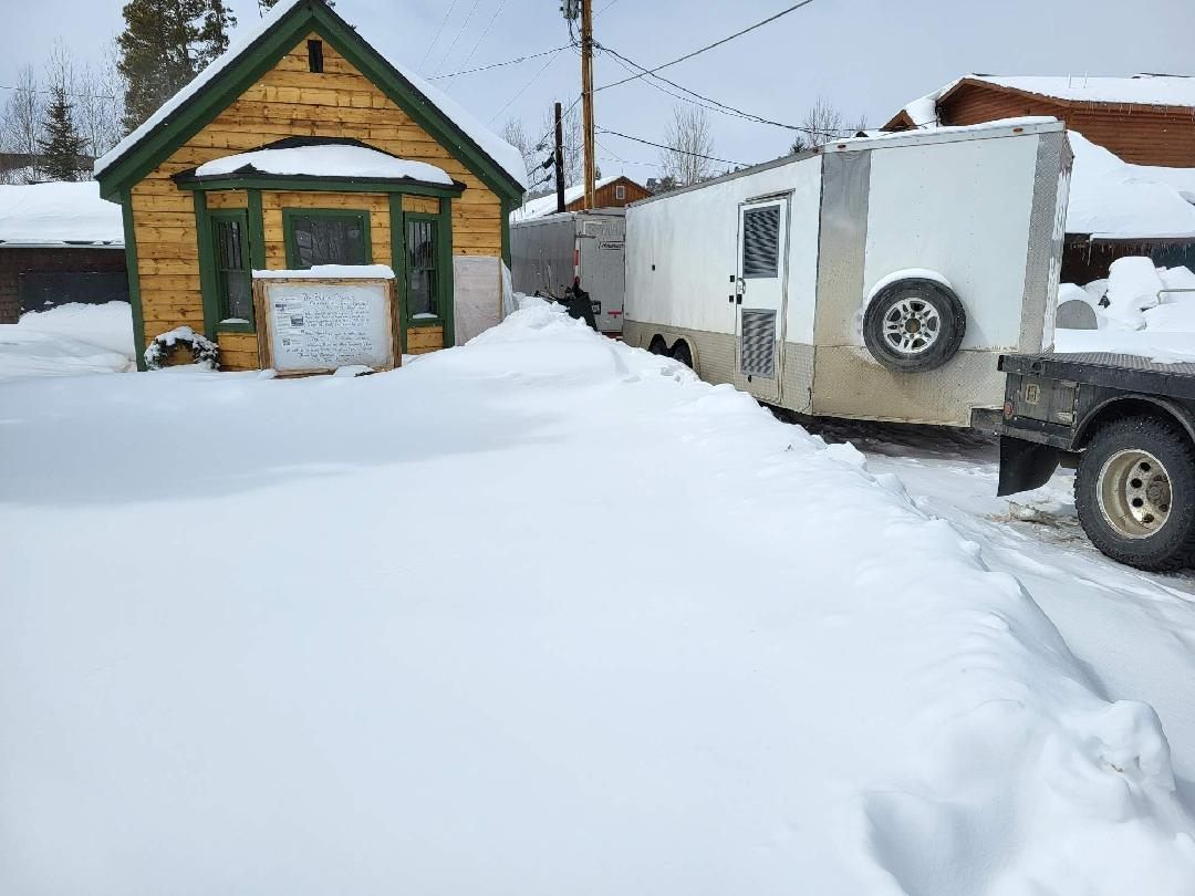 A trailer is sitting in the snow in front of a house.