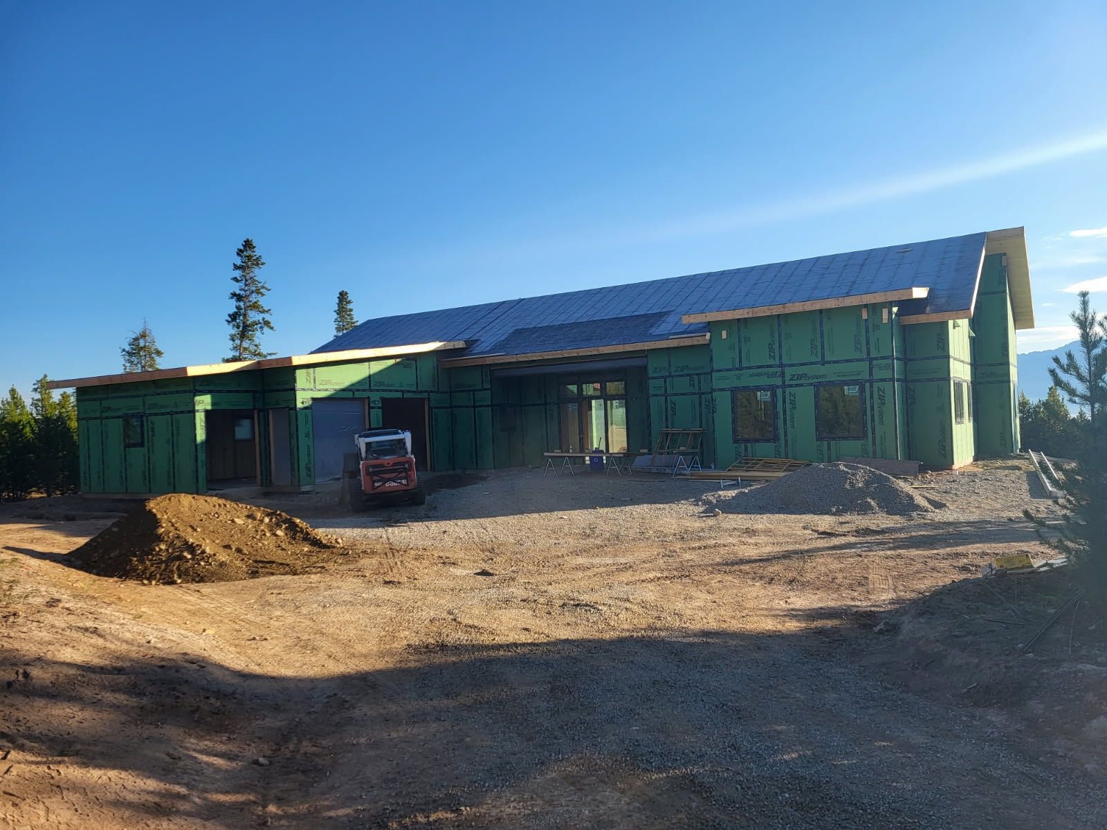 A large house is being built in the middle of a dirt field