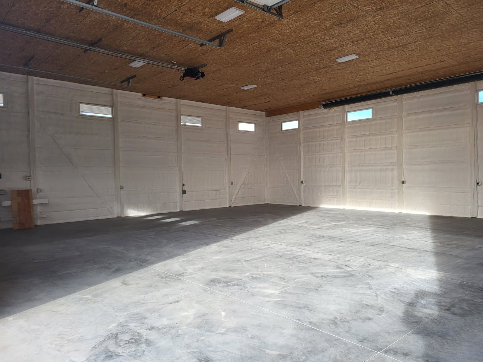 A large empty garage with a wooden ceiling and concrete floor.