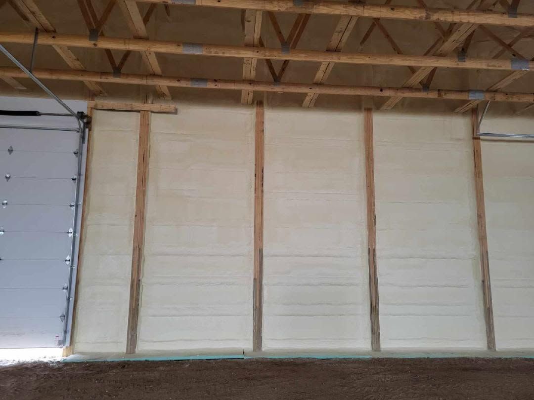 A garage with a door and a wall covered in insulation.