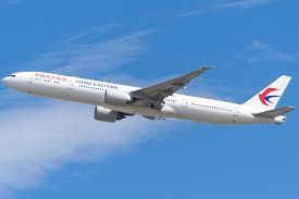 China Eastern Airlines Boeing 777 airplane soaring through a blue sky with clouds.