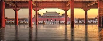 View of the Forbidden City in Beijing, China, framed by red pillars and rooftops at sunset.
