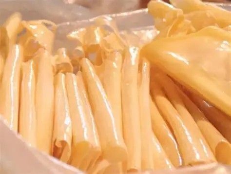 Pale yellow tubes, likely food, tightly packed in a container.