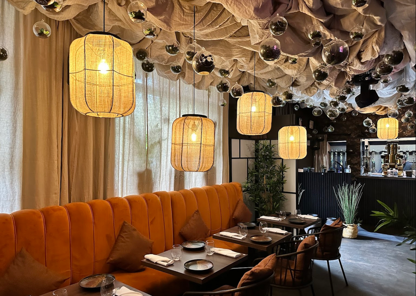 A restaurant with tables and chairs and lanterns hanging from the ceiling.