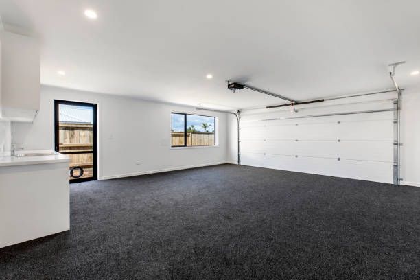 Empty garage with dark gray carpet, white walls, and a closed garage door.