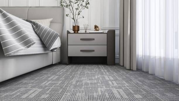 Bedroom with gray carpet, bed, nightstand with decor, and sheer curtains.