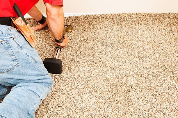Man installing carpet with a hammer in a room.