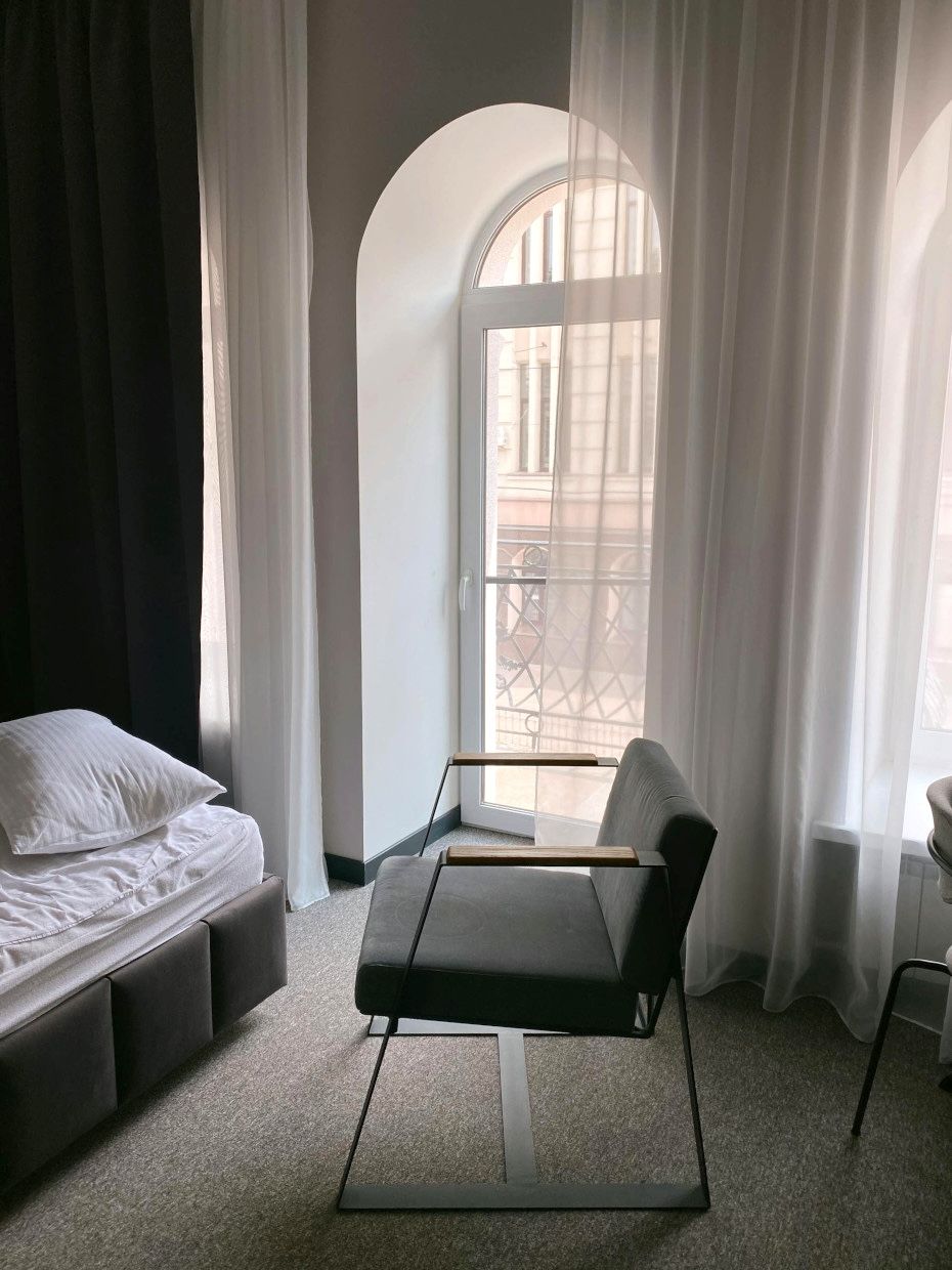 A bedroom with a bed , chair , and window.