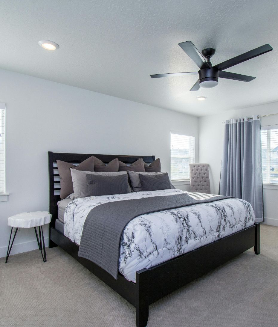 A bedroom with a large bed and a ceiling fan