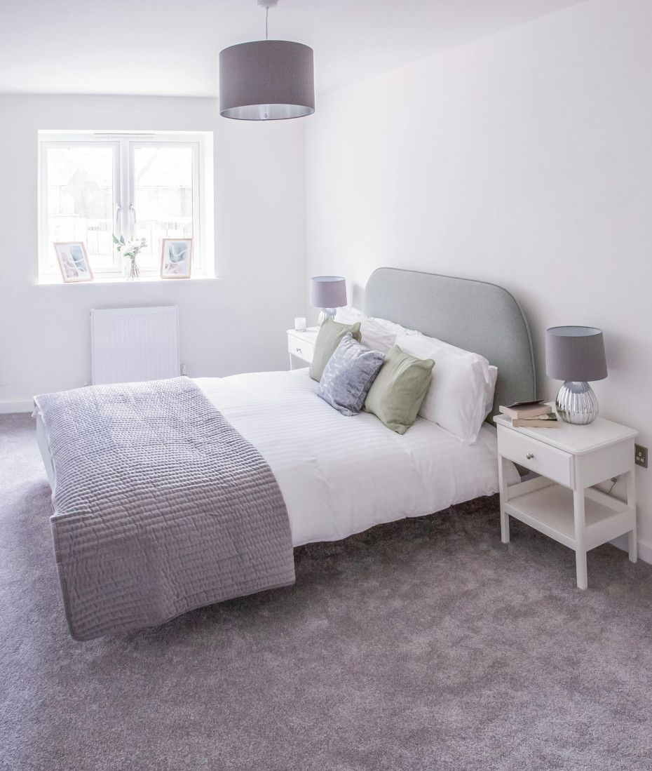 A bedroom with a bed , nightstand , lamps and a window.