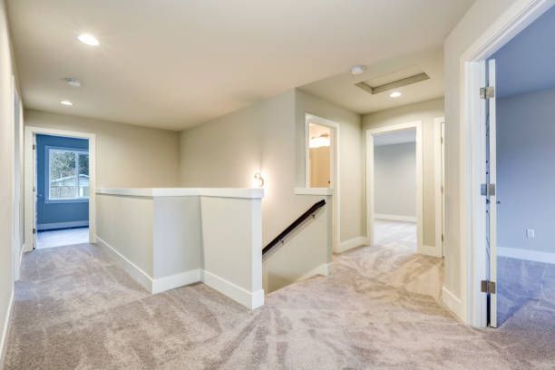 Hallway with gray carpet, walls, and doorways, plus a white banister and stairs.