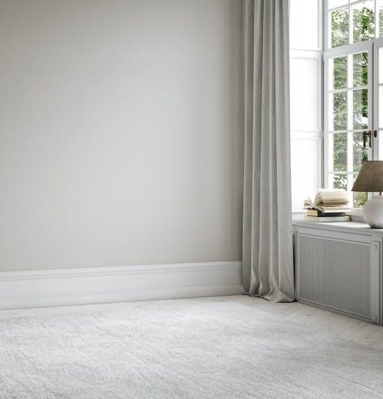 Empty room with gray carpet, window with curtains, and radiator.
