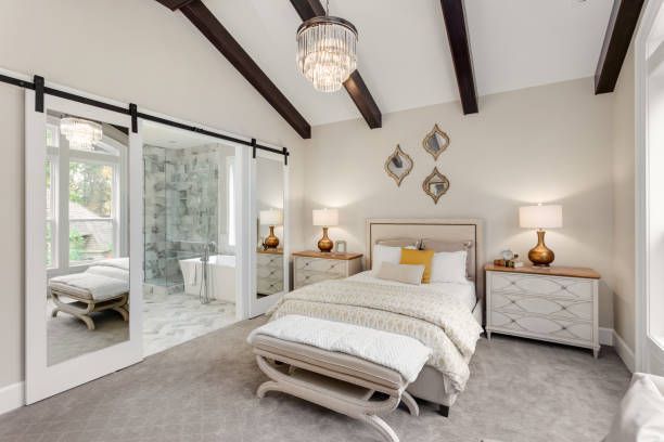 Bedroom with mirrored sliding doors to bathroom, bed, nightstands, and chandelier.