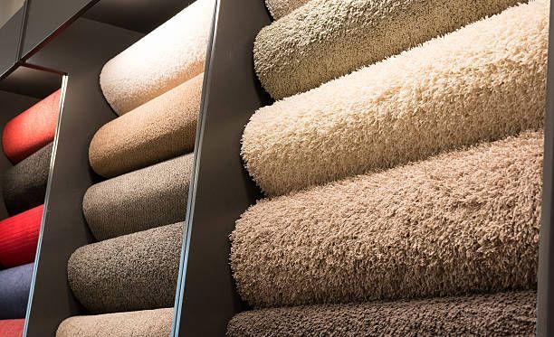 Carpet samples rolled and stacked in a display. Beige, gray, and red hues.