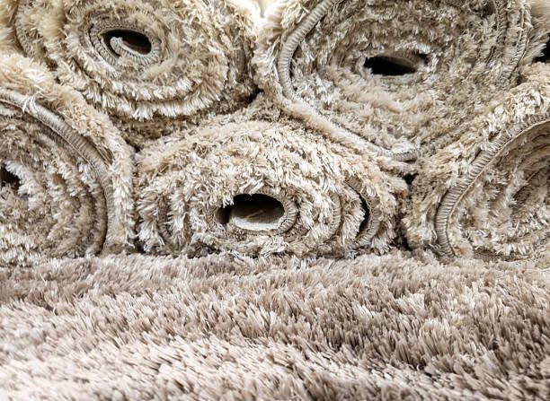 Rolled beige carpet with a shaggy, textured surface.