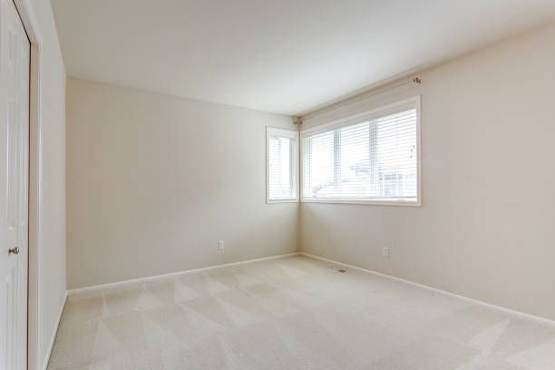 Small empty room with cream painted walls and soft wall-to-wall carpet