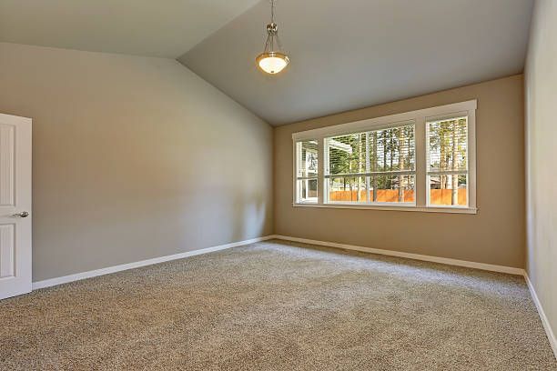Brand new house construction interior. Beige empty room with vaulted ceiling and carpet floor