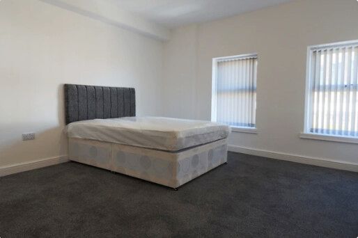Bedroom with a bed, windows, and dark carpet.