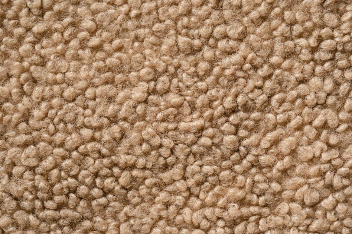 Close-up view of textured, tan-colored sheepskin fabric.