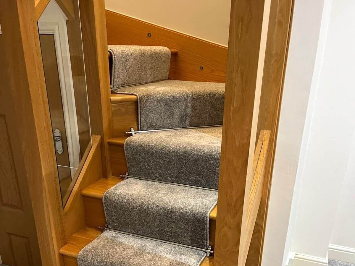 Wooden staircase with gray carpet runner.