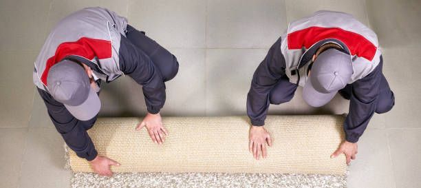 Male worker unrolling carpet on floor at home