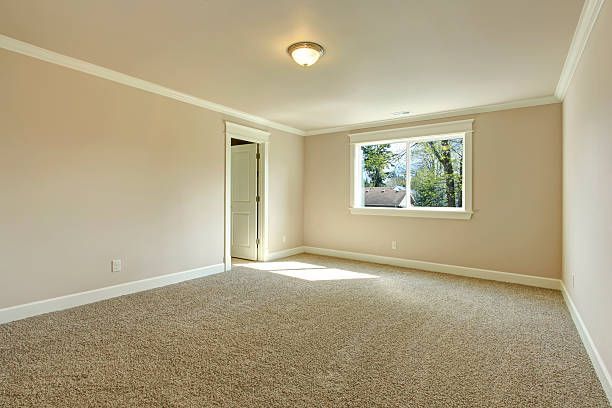Bright empty room with one window, beige carpet floor and ivory walls