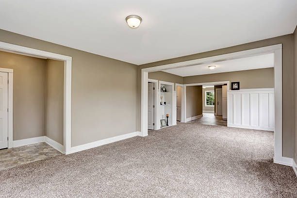 Empty room with beige carpet and walls, white trim, and a hallway.